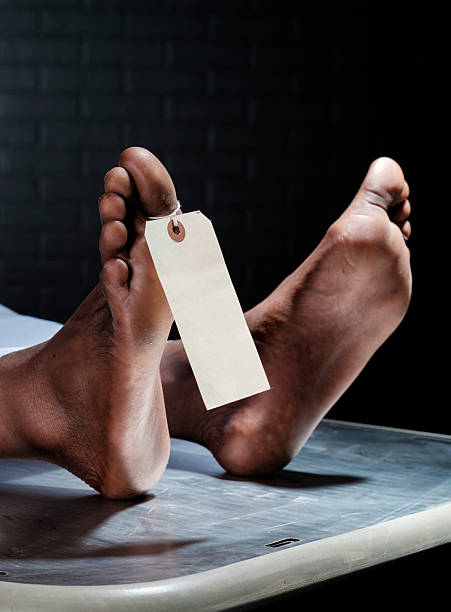 A close-up of the foot of a dead person in a morgue. A blank tag is attached to the toe.